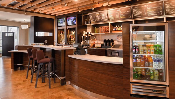 A bar area with stools, a refrigerated drink display, and a menu board.