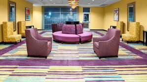 Un hall d’entrée avec un espace salon central, des murs jaunes et une moquette à motifs.
