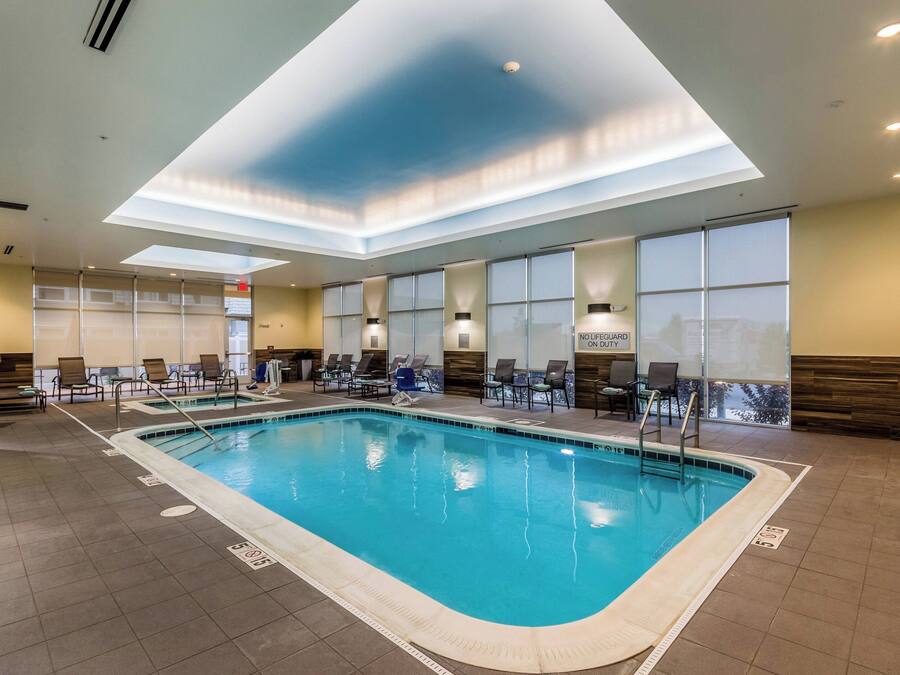 An indoor swimming pool with clear water, surrounded by lounge chairs and a sunroof ceiling.