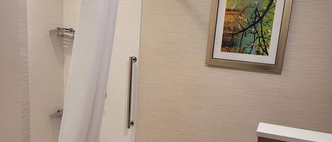 A bathroom with a bathtub, toilet, and a framed picture on the wall.