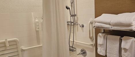 A modern bathroom with a bathtub, shower, and towel rack.