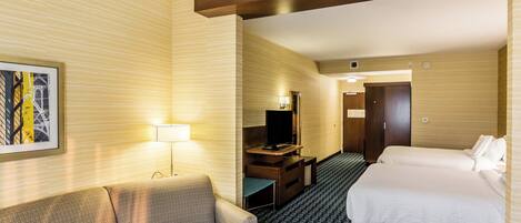 A hotel room with a sofa, a bed, a TV, and a desk.