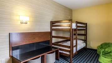 Un lit superposé avec un bureau et deux chaises, une lampe fixée au mur et un fauteuil en forme de haricot vert.