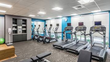 A gym with treadmills, elliptical machines, and a bench.