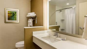 A modern bathroom with a white sink, a large mirror, a shower with a glass door, and a towel rack with folded towels.