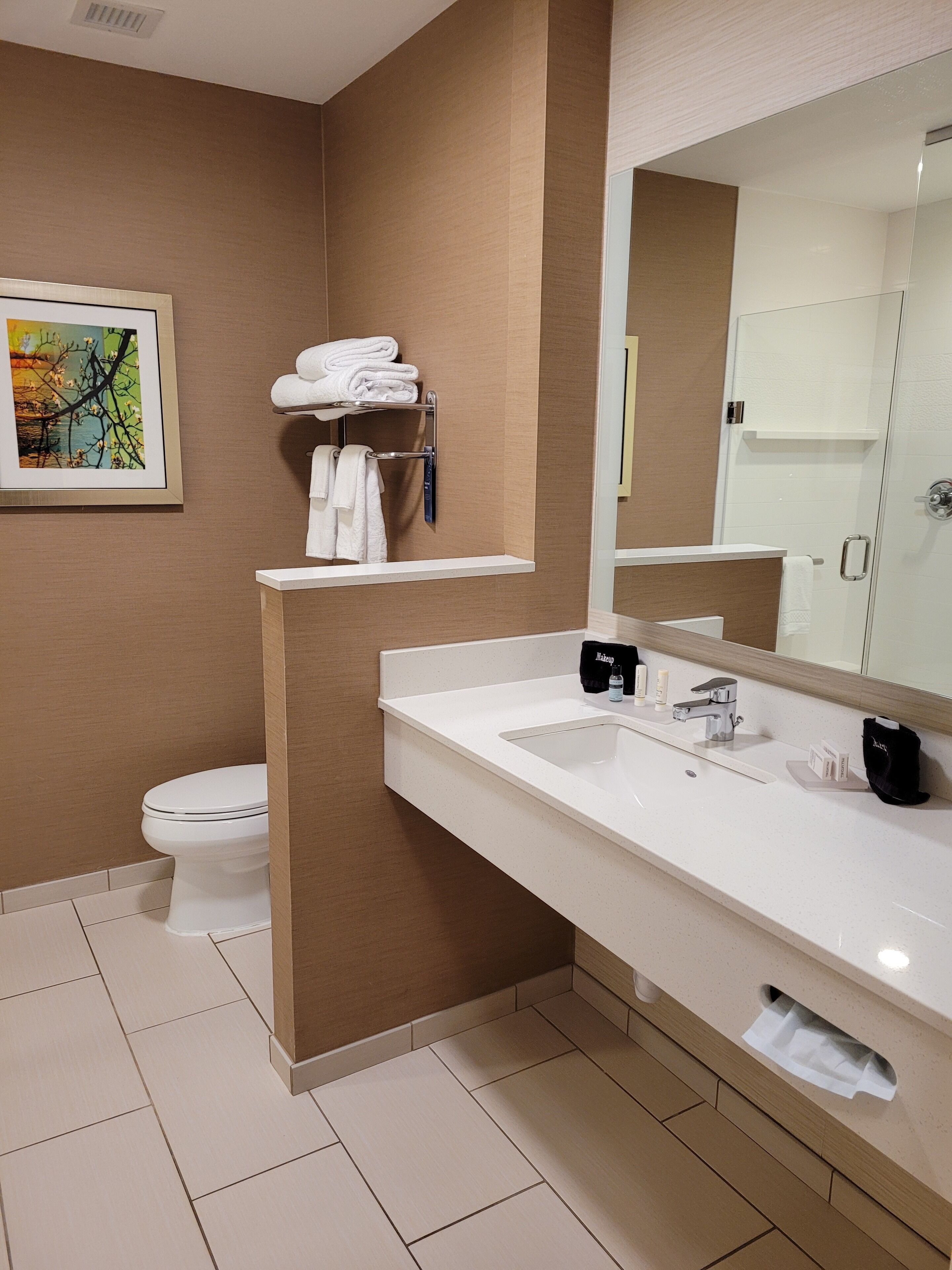 A modern bathroom with a white sink, a large mirror, and a towel rack.