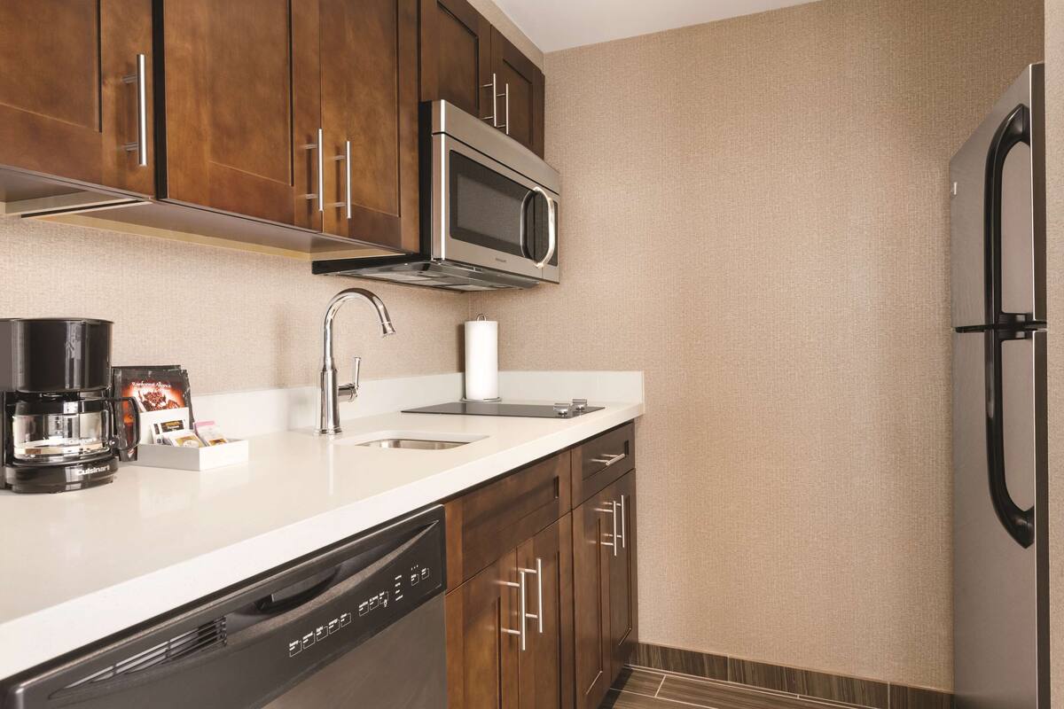 Una cocina moderna con electrodomésticos de acero inoxidable, lavavajillas y armarios de madera.