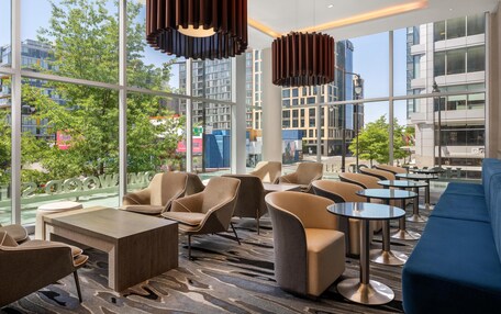 A modern hotel lobby with large windows, comfortable seating, and contemporary lighting.