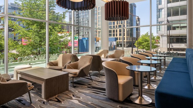 Eine moderne Hotelhalle mit großen Fenstern, bequemen Sitzgelegenheiten und zeitgemäßer Beleuchtung.