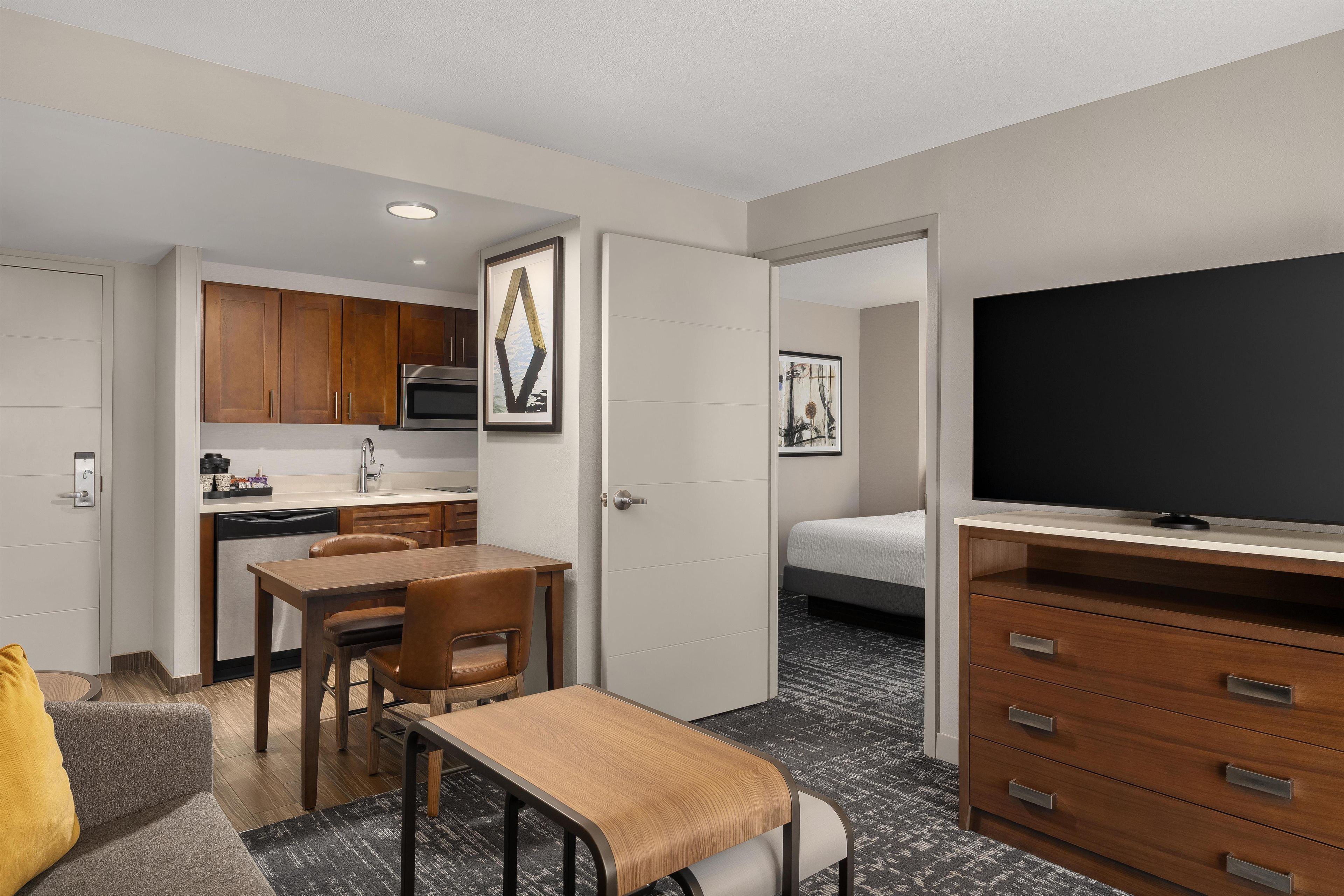 Une chambre d’hôtel compacte comprenant un coin cuisine, un espace repas, une télévision et un lit.