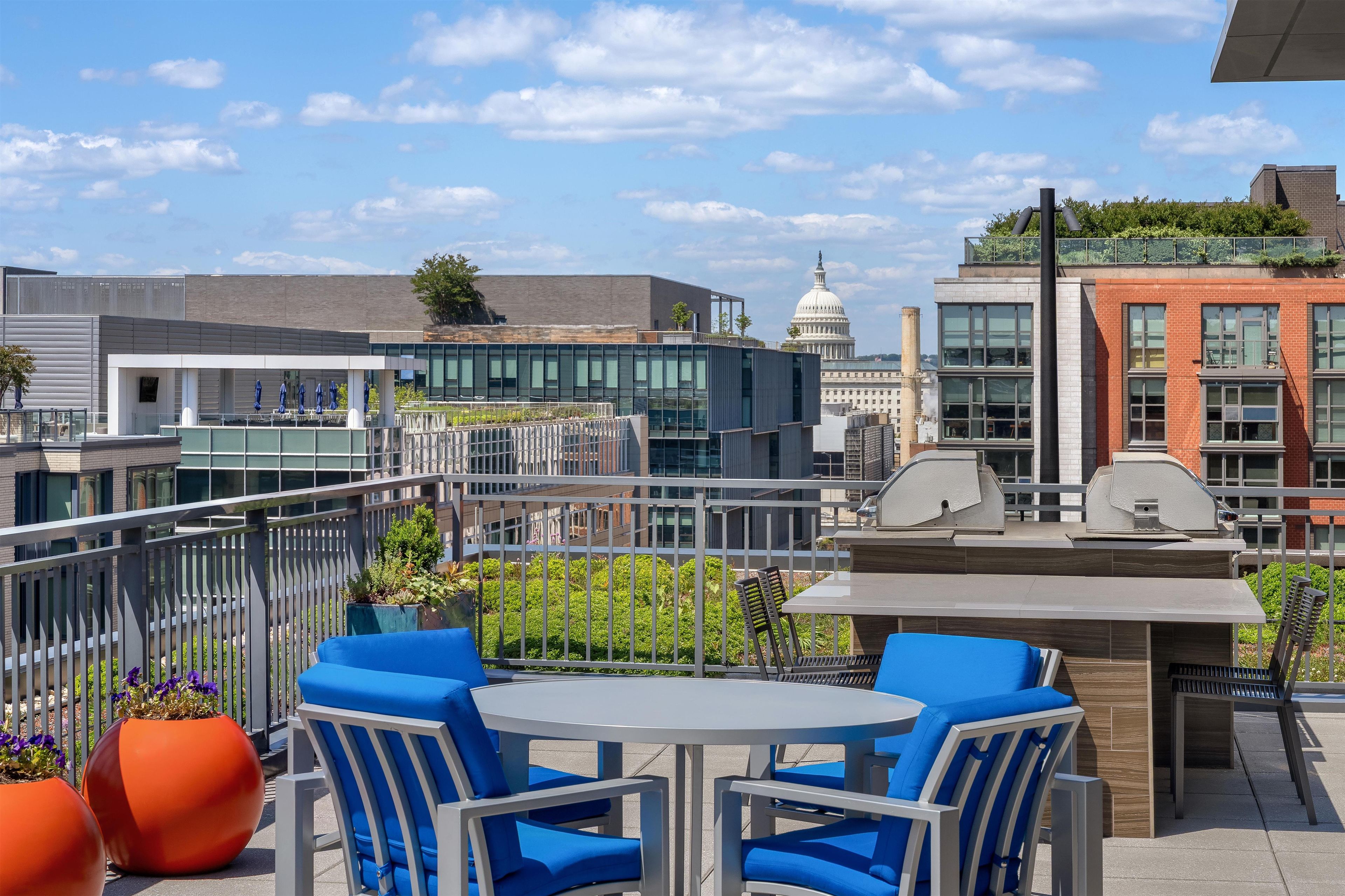 A rooftop patio with outdoor seating, a grill, and a view of the Capitol building.