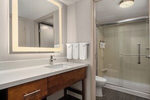 Baño con lavamanos, espejo y cabina de ducha de vidrio.