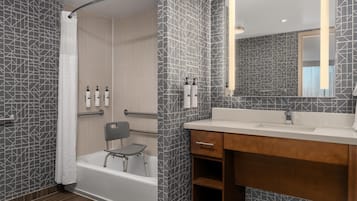 A modern bathroom with a shower, a bathtub, a vanity with a mirror, and toiletries on the wall.