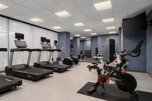 Un gimnasio con cintas de correr, elípticas y una bicicleta estática.