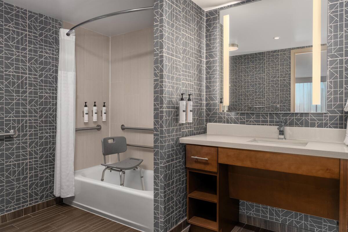 Un baño moderno con ducha, bañera, tocador con espejo y artículos de aseo en la pared.