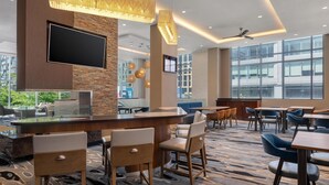 Eine moderne Hotelhalle mit Barbereich, Sitzgelegenheiten und großen Fenstern.