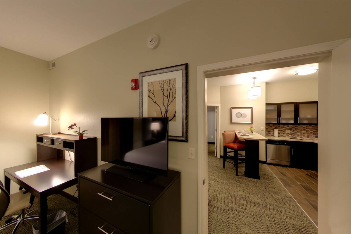 Une chambre d’hôtel équipée d’un bureau, d’une chaise, d’une télévision et d’une kitchenette.