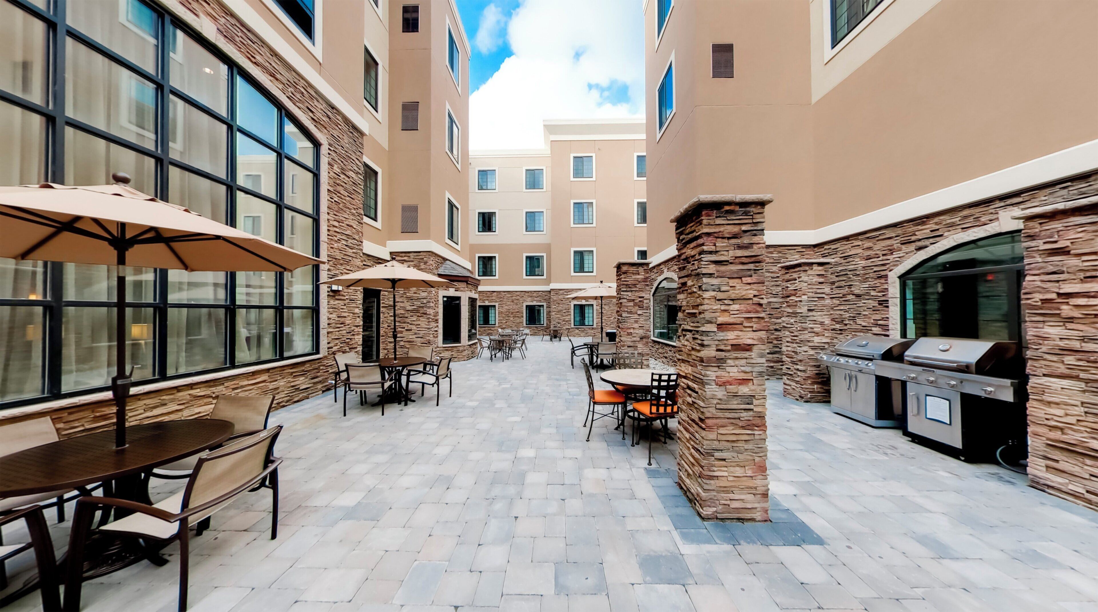 A courtyard with outdoor seating, stone pillars, and a barbecue area.