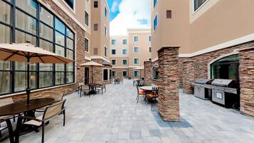 A courtyard with outdoor seating, stone pillars, and a barbecue area.