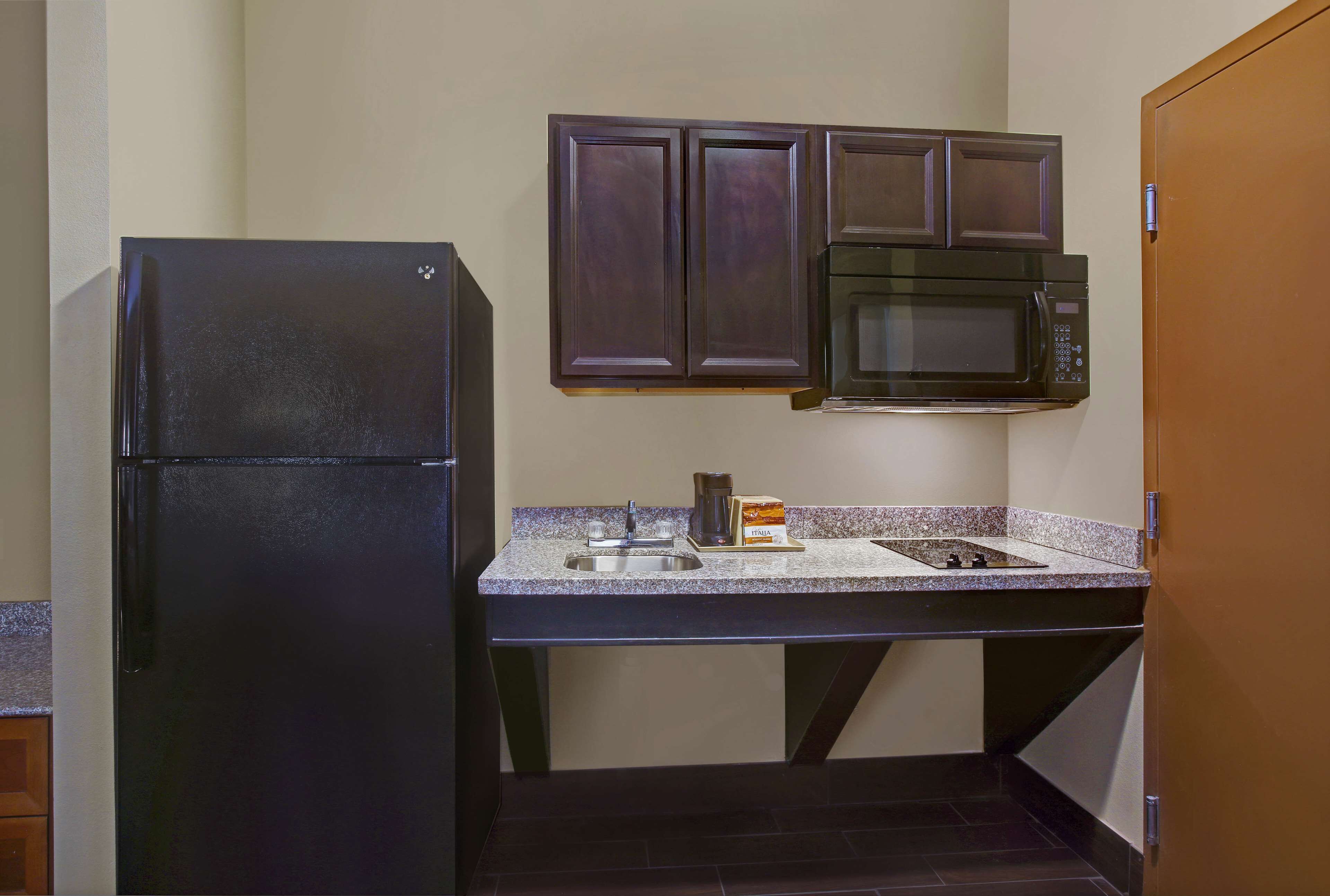 Una cocina compacta equipada con refrigerador, microondas y lavamanos.