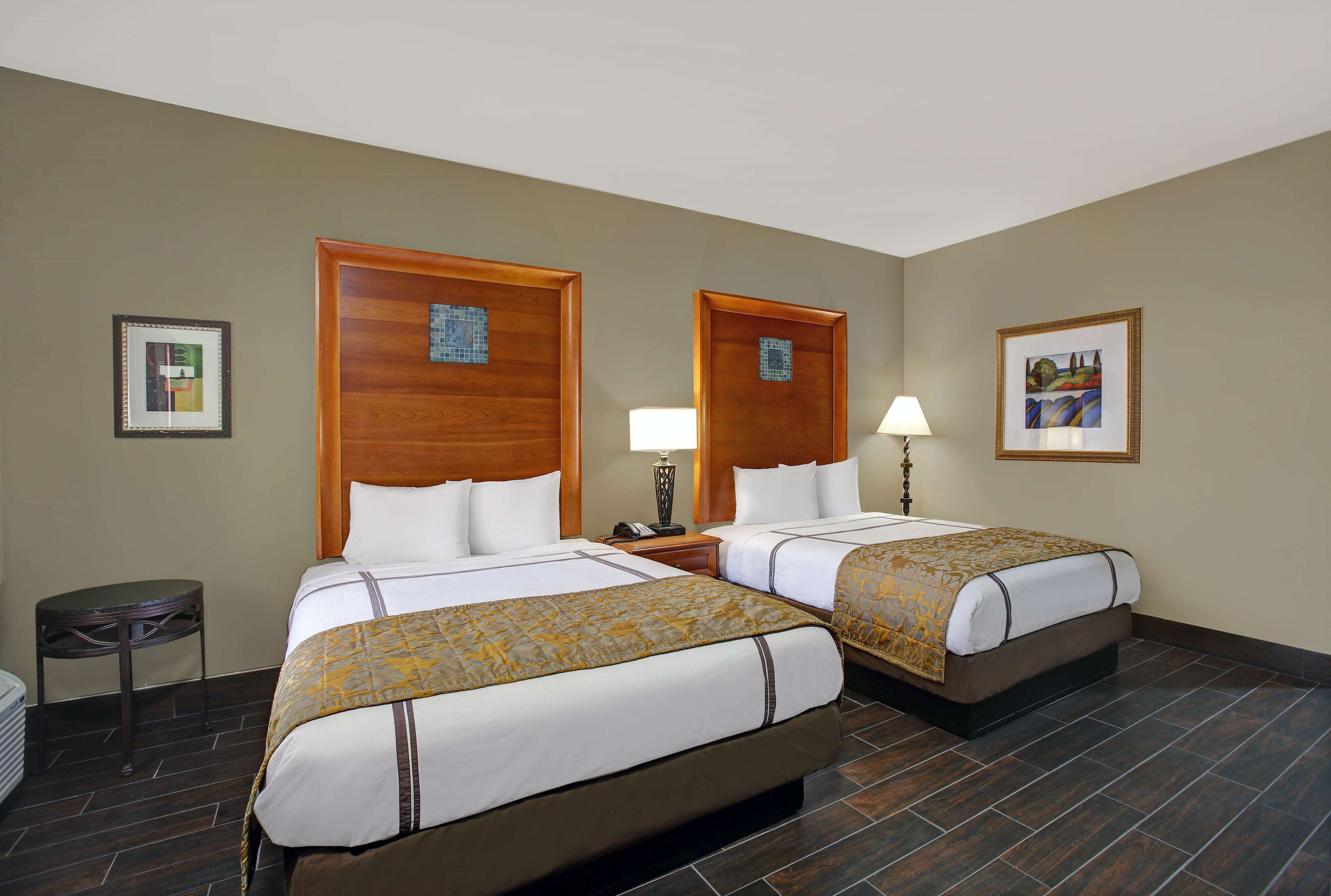 A hotel room with two beds, a small round table, and a trash bin.