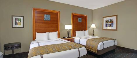 A hotel room with two beds, a small round table, and a trash bin.