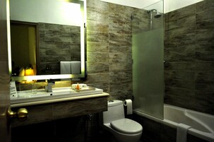 A modern bathroom with a glass-enclosed shower, a toilet, and a sink with a mirror.