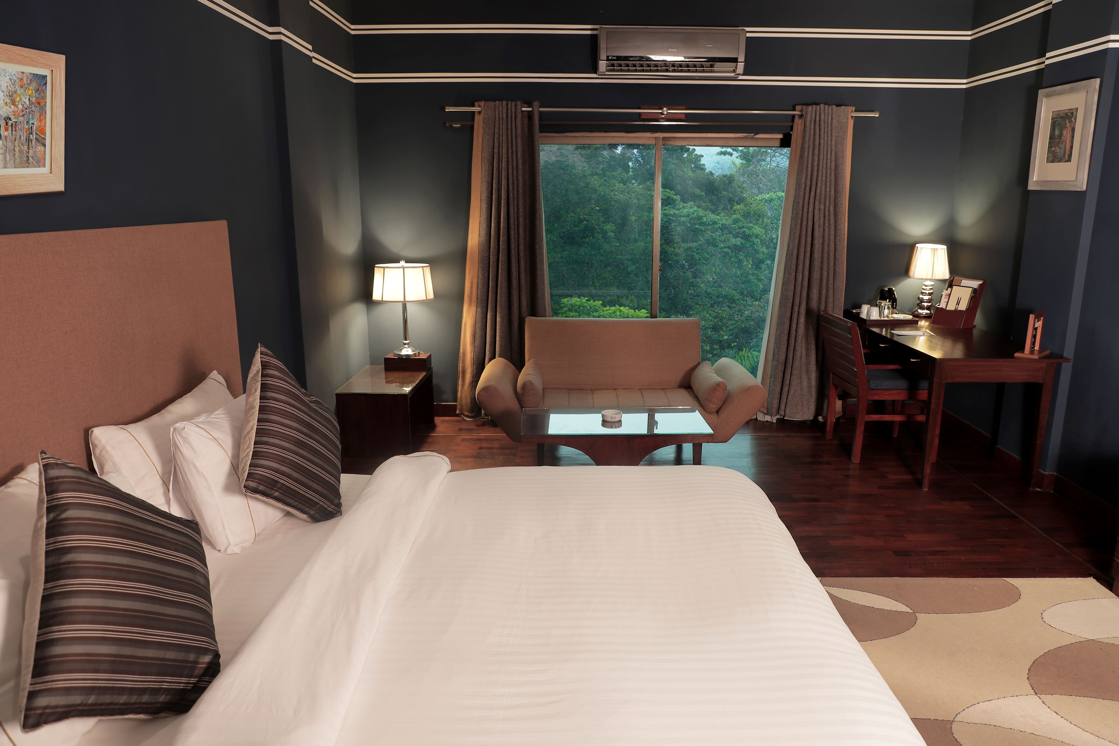 Habitación de hotel con una cama grande, un escritorio, una silla y vistas al exterior.