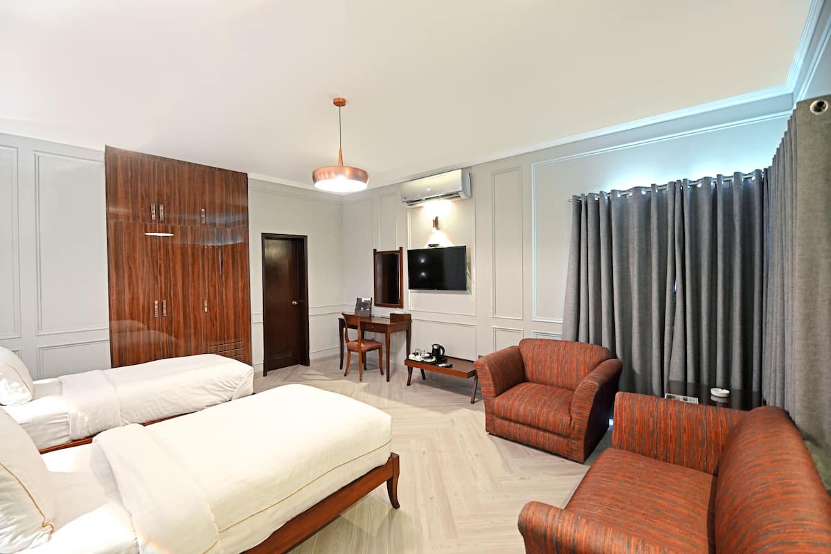 A hotel room with two beds, a desk, a chair, and a sofa.