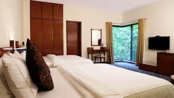 A hotel room with a large bed, a wardrobe, a desk with a chair, a television, and a window with curtains.
