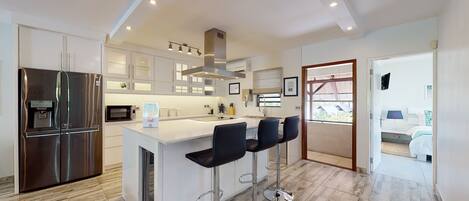 A modern kitchen with a central island, stainless steel appliances, and a bar area with stools.