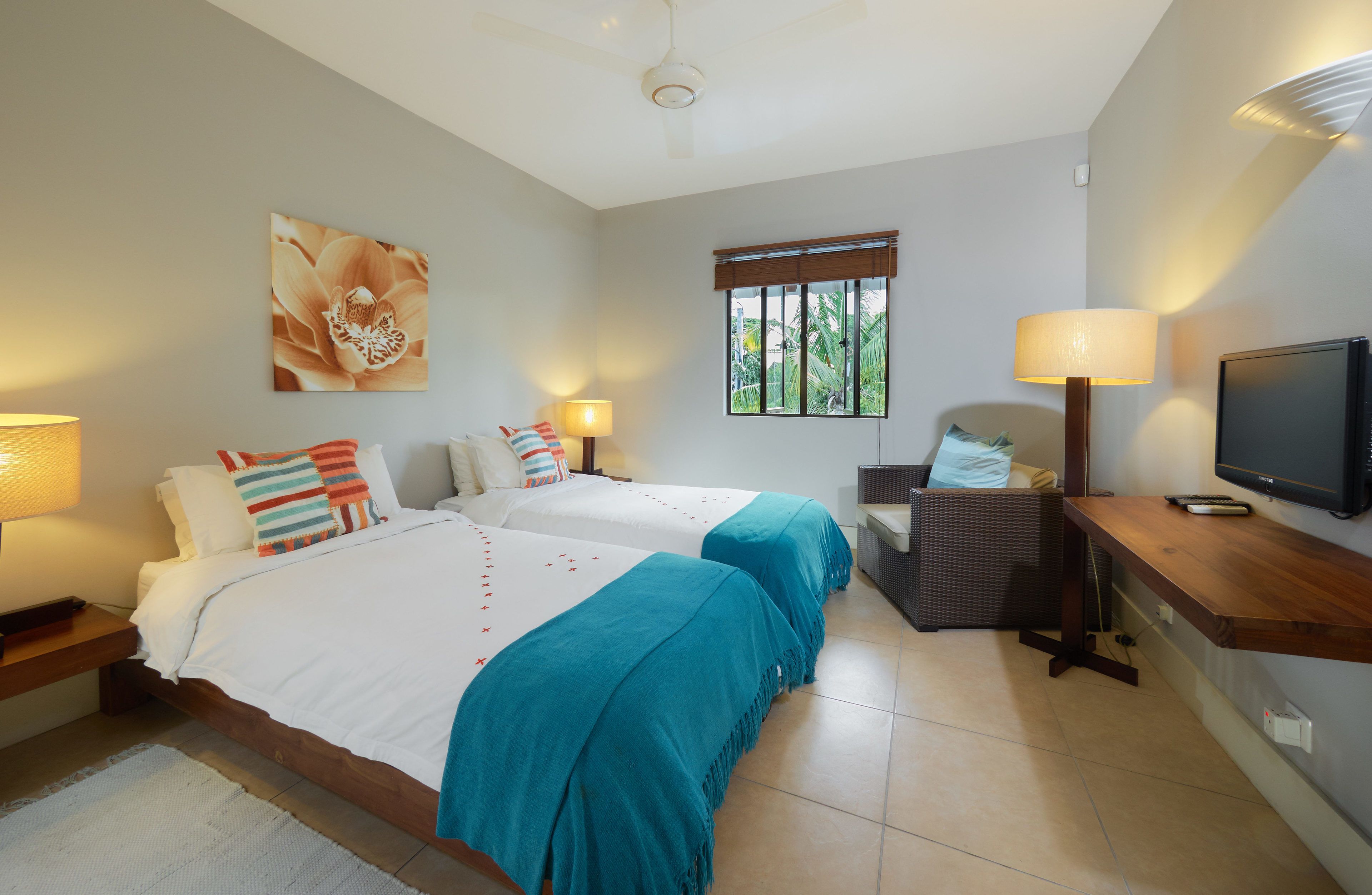 A hotel room with two beds, a television, a window with blinds, and a chair.