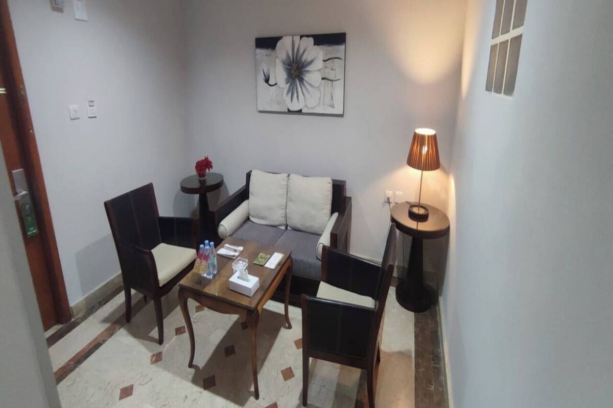 A living area with a sofa, two armchairs, a coffee table, and a lamp.
