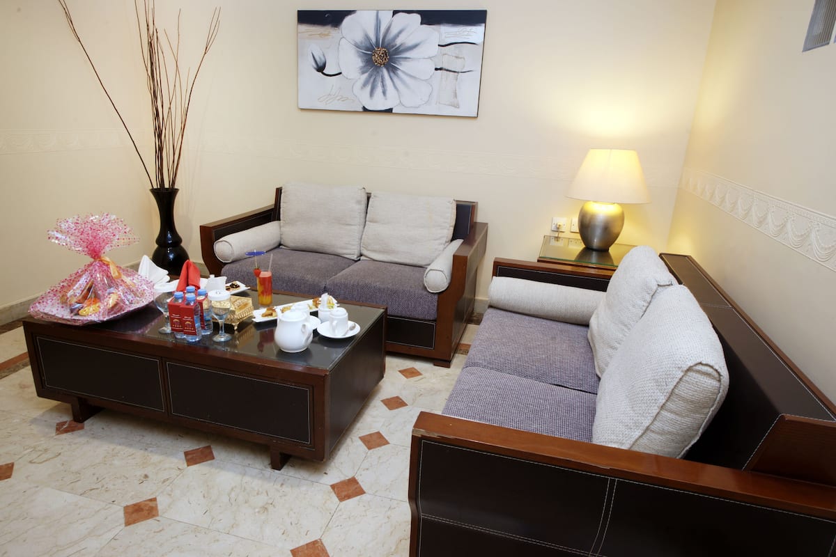 A living room with a sofa, a coffee table, a lamp, and a painting on the wall.
