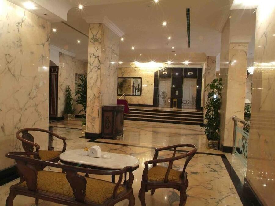 A lobby with marble flooring, a reception desk, and a staircase leading to an upper level.