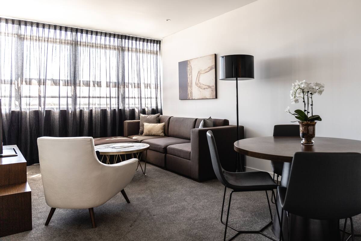 A modern living room with a sofa, armchairs, a coffee table, and a dining table.
