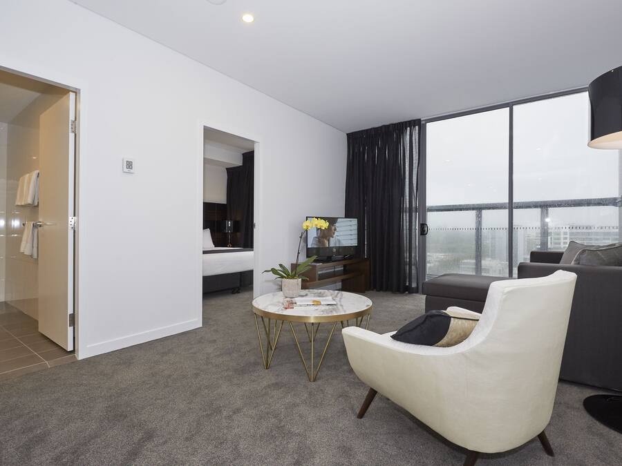 A modern living room with a sofa, armchair, and a round coffee table with a plant.