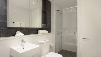 A modern bathroom with a white sink, toilet, and glass-enclosed shower.