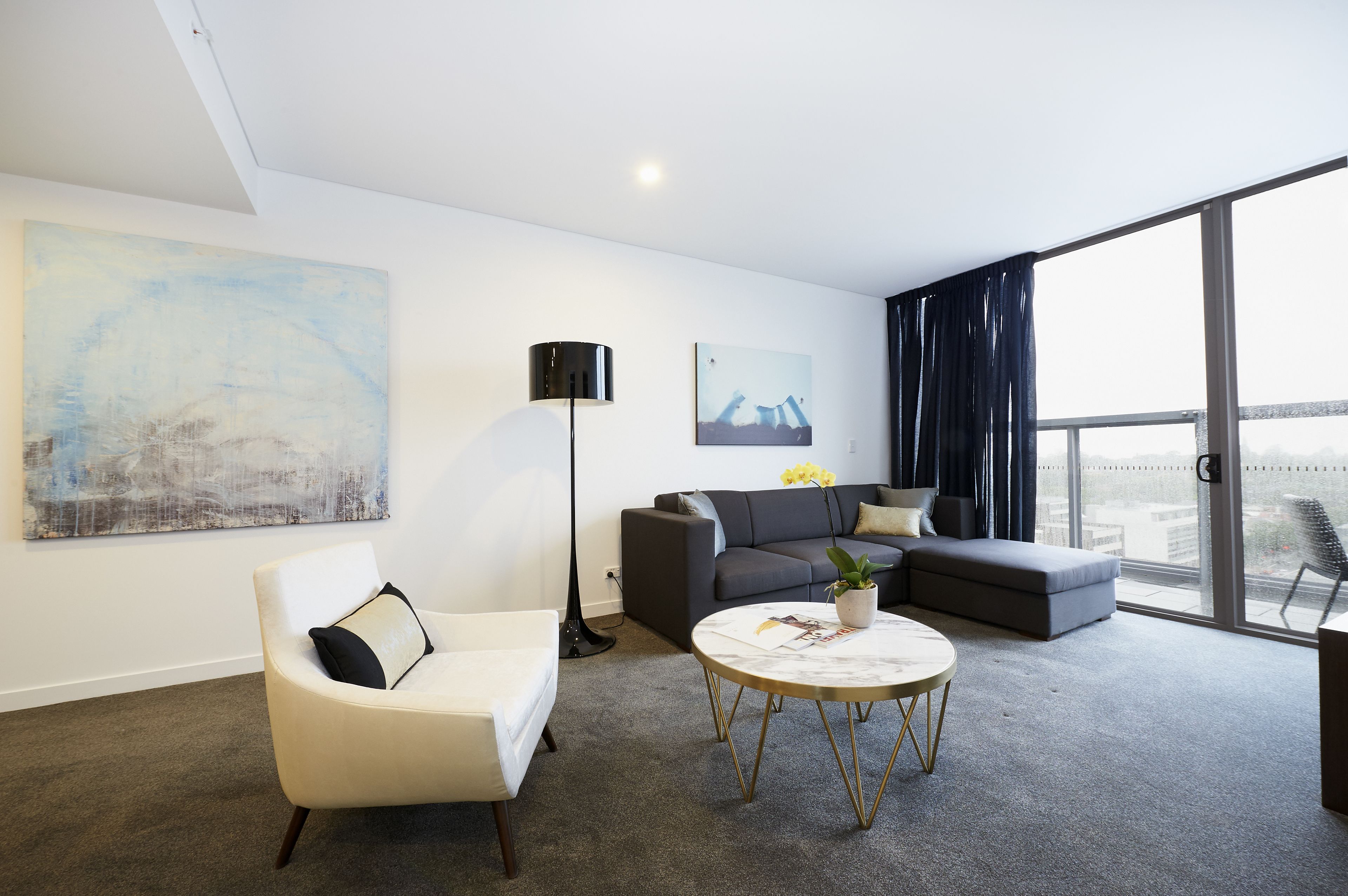 A modern living room with a sofa, armchair, and round coffee table.