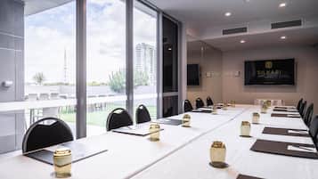Un salón de conferencias con una larga mesa, sillas y una pantalla de televisión que muestra 'SILKARI SUITES'.