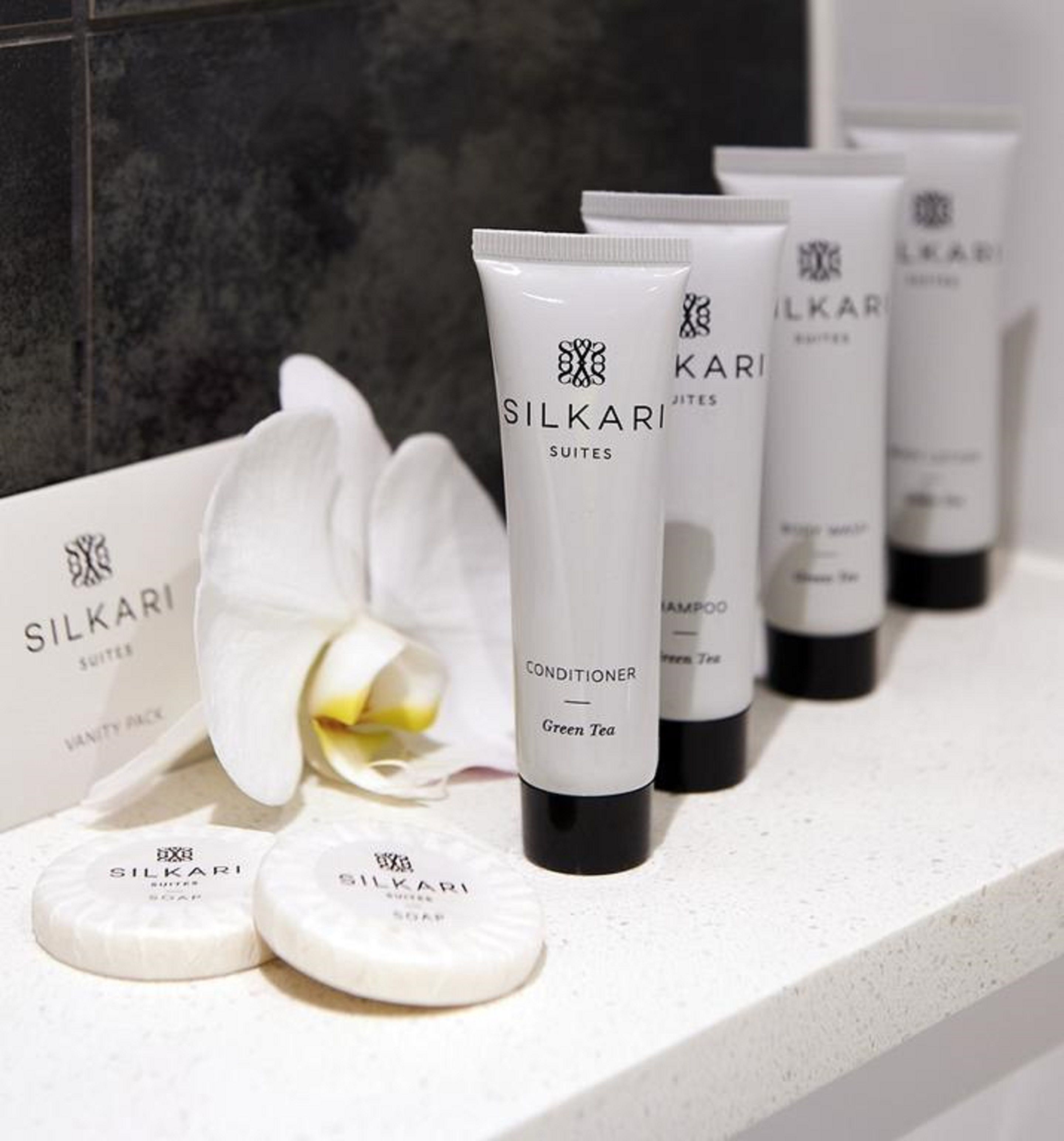 A bathroom counter with Silkari toiletries, including a conditioner, shampoo, and soap.