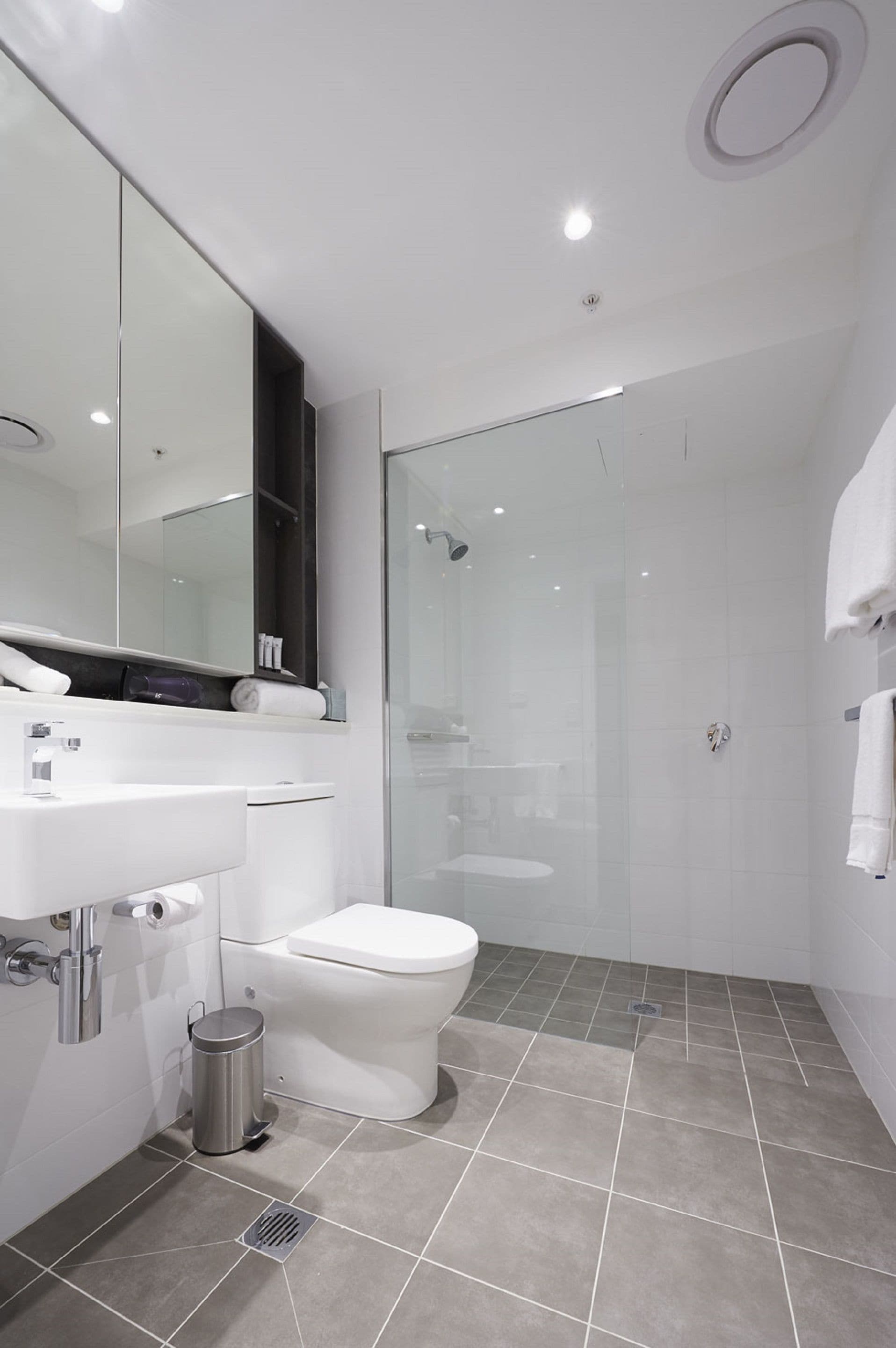 Une salle de bain moderne avec un lavabo blanc, des toilettes et une douche à parois de verre.