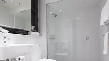 Une salle de bain moderne avec un lavabo blanc, des toilettes et une douche à parois de verre.
