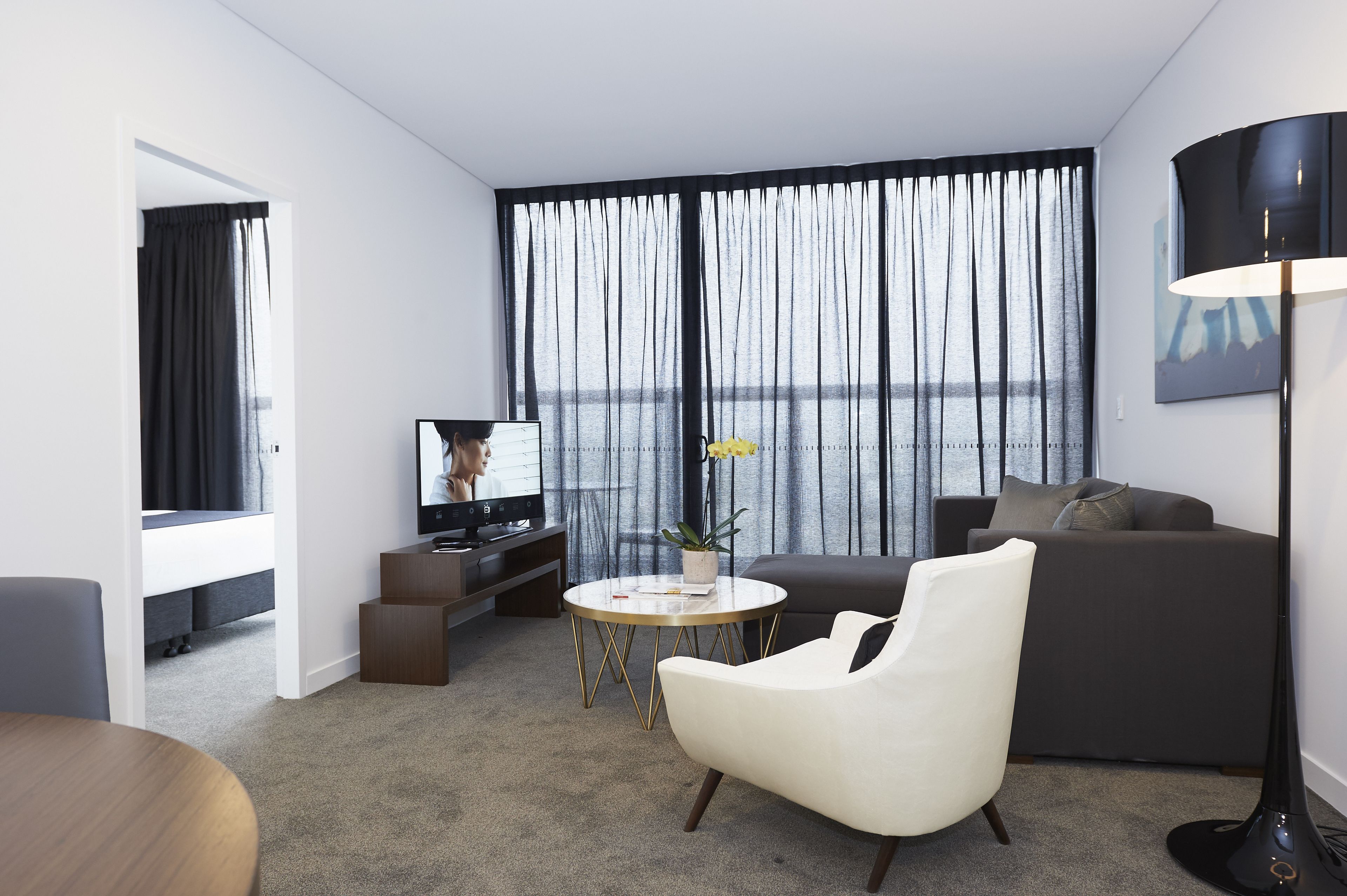 A modern living room with a sofa, armchair, coffee table, and a TV.