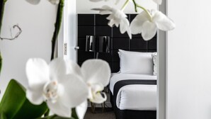 Una habitación de hotel moderna con cabecera negra, ropa de cama blanca y un ventanal grande.