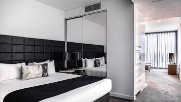 A modern hotel room with a large bed, a black headboard, a bedside table with a lamp, and a large mirror.