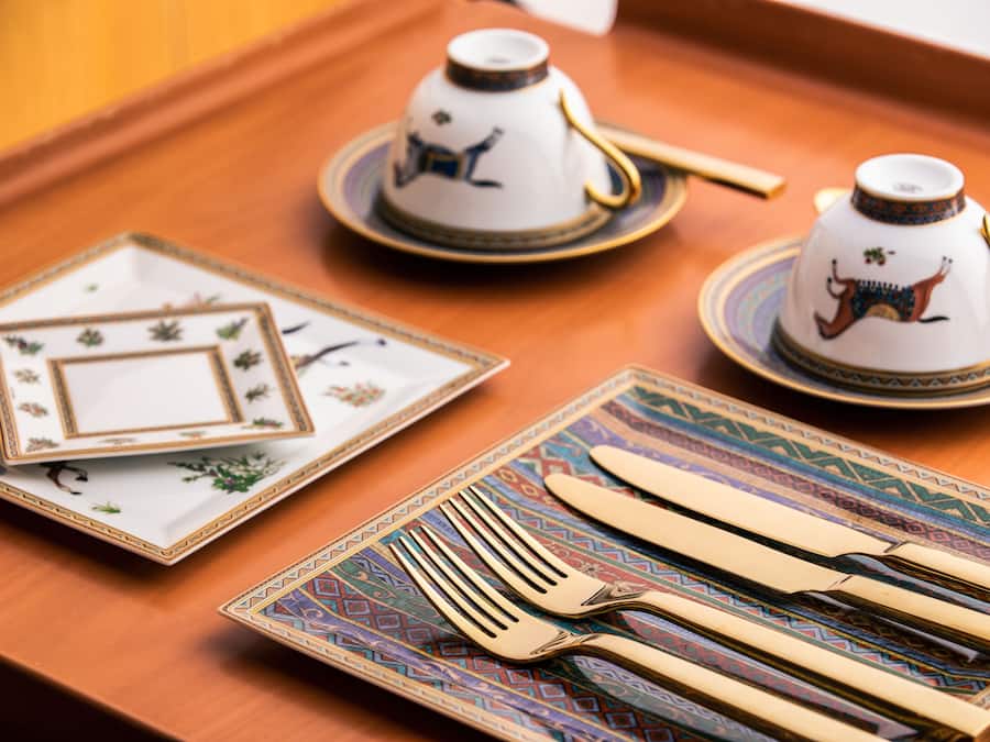 Una bandeja con una tetera, tazas de té, una vela para té, y muchas tazas más.