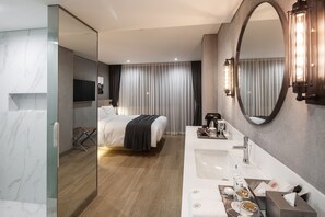 A modern hotel room with a large bed, a glass-enclosed shower, a vanity with a sink and mirror, and a flat-screen TV. - Hotel28 Myeongdong (Seoul)