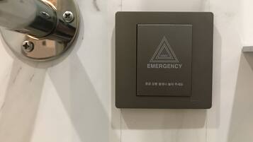 Un botón de emergencia fijado a la pared, con un logo triangular y texto.