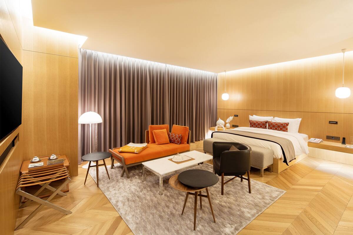 A modern hotel room with a sofa, bed, and a small table.